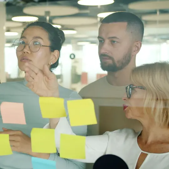 Team organising ideas with sticky notes on a glass wall